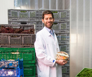 Ein Mann steht in einem Kühlhaus, umgeben von frischen Gemüse