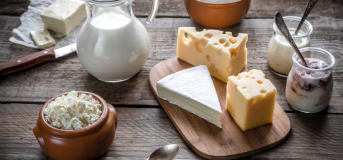 Verschiedene Käsesorten, Milch, Joghurt und Butter auf Holztisch.