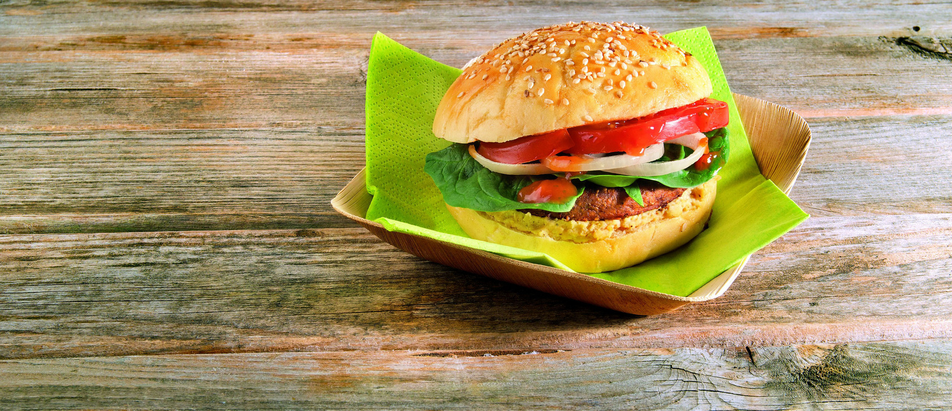 Burger mit Spinat und Hummus auf Holztisch