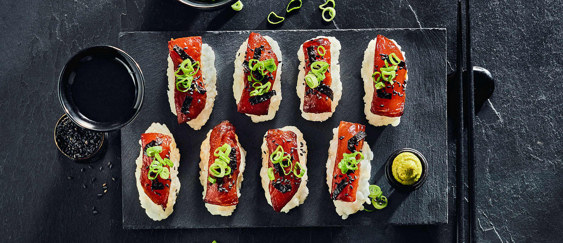 Reiskugeln mit einem Melonenfilet auf einem dunklen Brett