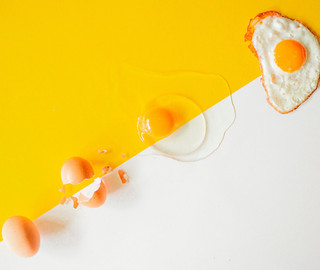 Ein Ei, ein zerbrochenes Ei, ein aufgeschlagenes Ei und ein Spiegelei liegen nebeneinander