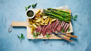Ein in Streifen geschnittenes Steak auf einem Holzbrett mit Kartoffeln