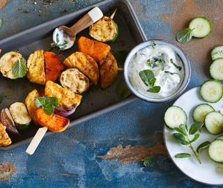 Vegane Grillspieße mit Tempeh, Süßkartoffeln und Zucchini an einem Dip aus Soja-Joghurt-Alternative und Gurken. Ein Symbolbild für vegan grillen.
