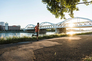 Mann joggt vor großer Brücke