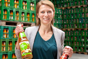 Das Bild zeigt die Ökotrophologin Jessica Liebetrau im Getränkelager mit einer Flasche Apfelsaft in der Hand.