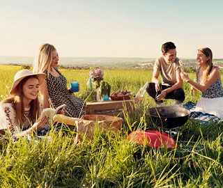 Eine Gruppe von Freunden sitzt auf einer Wiese, während sie picknicken.