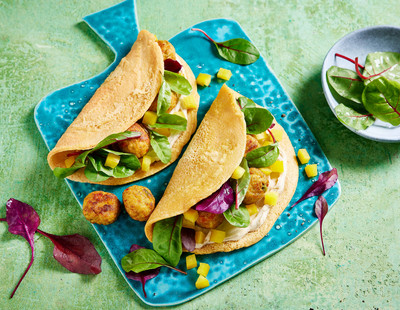 Drei Tacos mit Hühnchen, Avocado und Salat auf einem blauen Teller, dazu eine Schüssel mit Gemüse auf einer grün strukturierten Oberfläche.