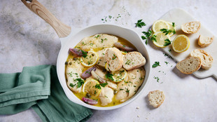 Hähnchen in einer weißen Pfanne garniert mit Zitronenscheiben und Baguette