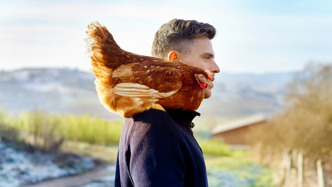 Wissen, woher Lebensmittel kommen mit dem Herkunftscheck fürs bewusste Genießen. Das Bild zeigt den Bio-Bauern Fabian Haede mit einem braunem Huhn auf seiner rechten Schulter.