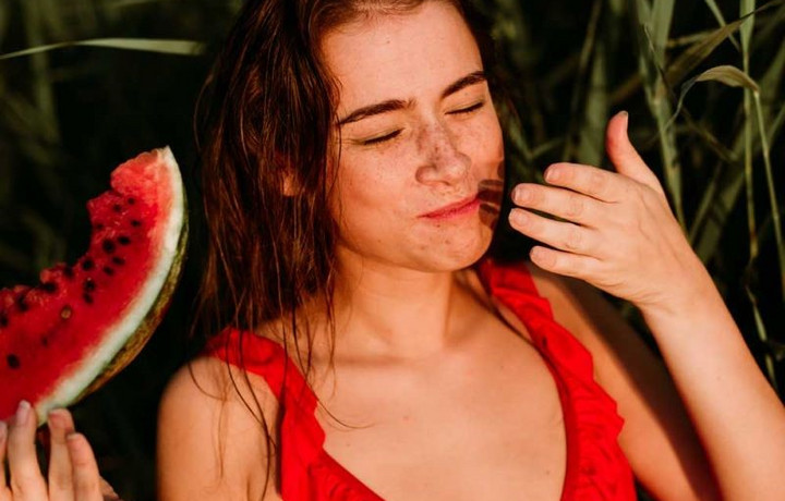 Junge Frau genießt ein Stück Wassermelone in der Sonne