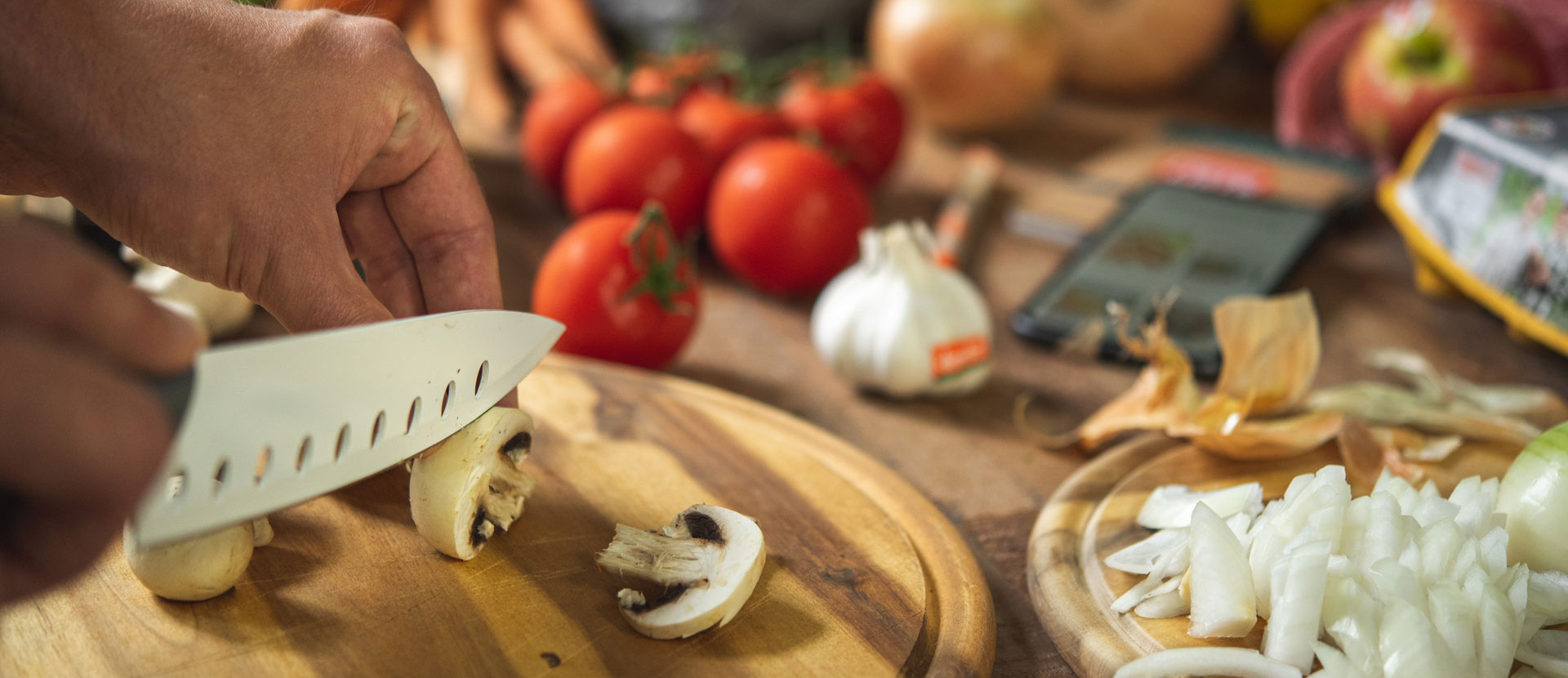 Kochwerkstatt schneiden mit Messer von pilzen auf holzbrett neben gemuese