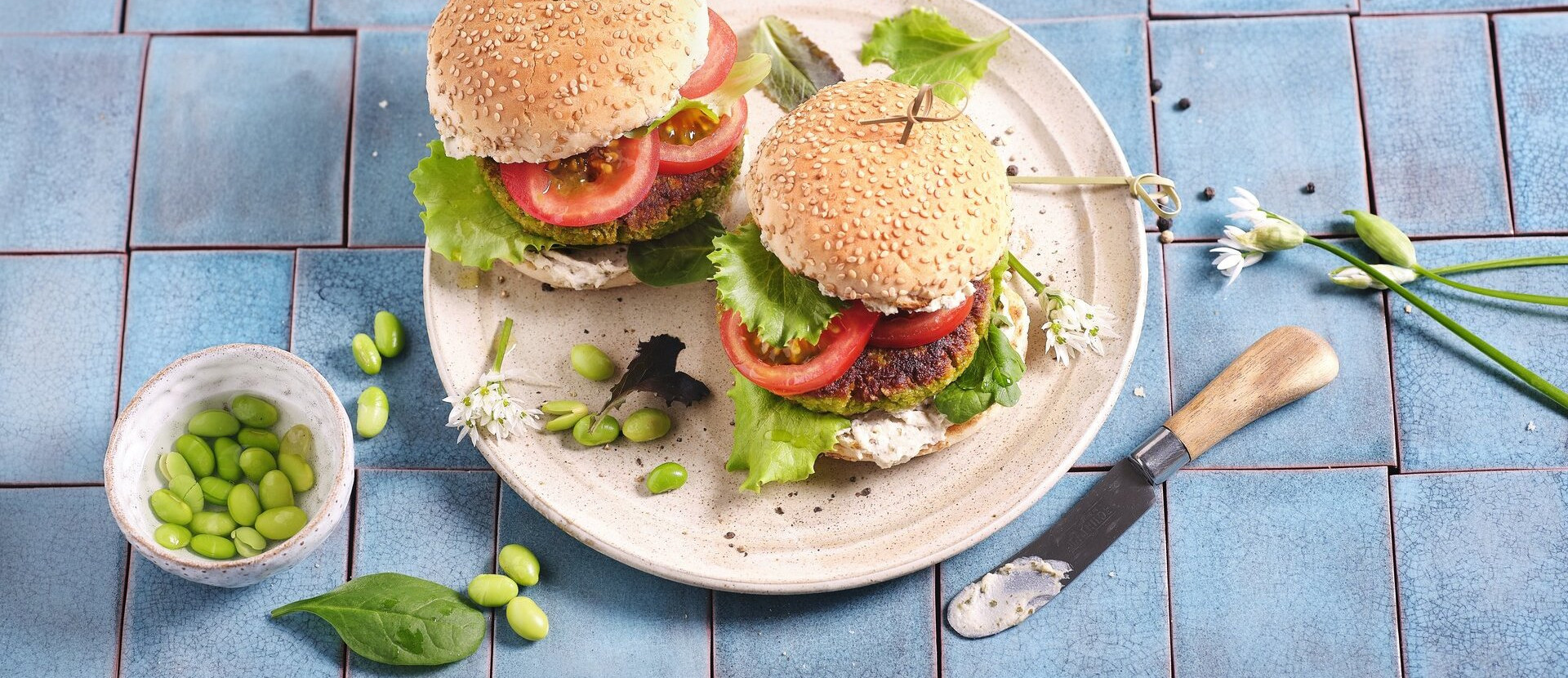 Das Bild zeigt zwei leckere vegane Burger mit Protein Patty, grünen Salatblättern und Tomatenscheiben.