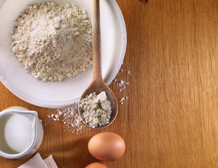 Mehl in Schüssel mit Milch und Eiern