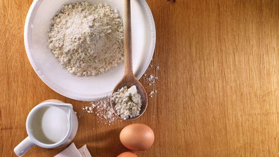 Mehl in Schüssel mit Milch und Eiern