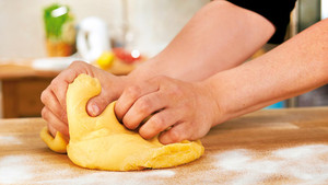 Zwei Hände kneten einen Pastateig