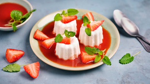 vegane Erdbeer Panna Cotta mit roter Erdbeersauce präsentiert auf einem weißem Teller