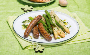 Lamm-Bratwürstchen mit grünem und weißem Spargel auf einem Teller