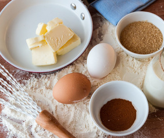 Holz-Arbeitsfläche mit Mehl, Eiern, Kakaopulver, Butter, Zucker und Milch.
