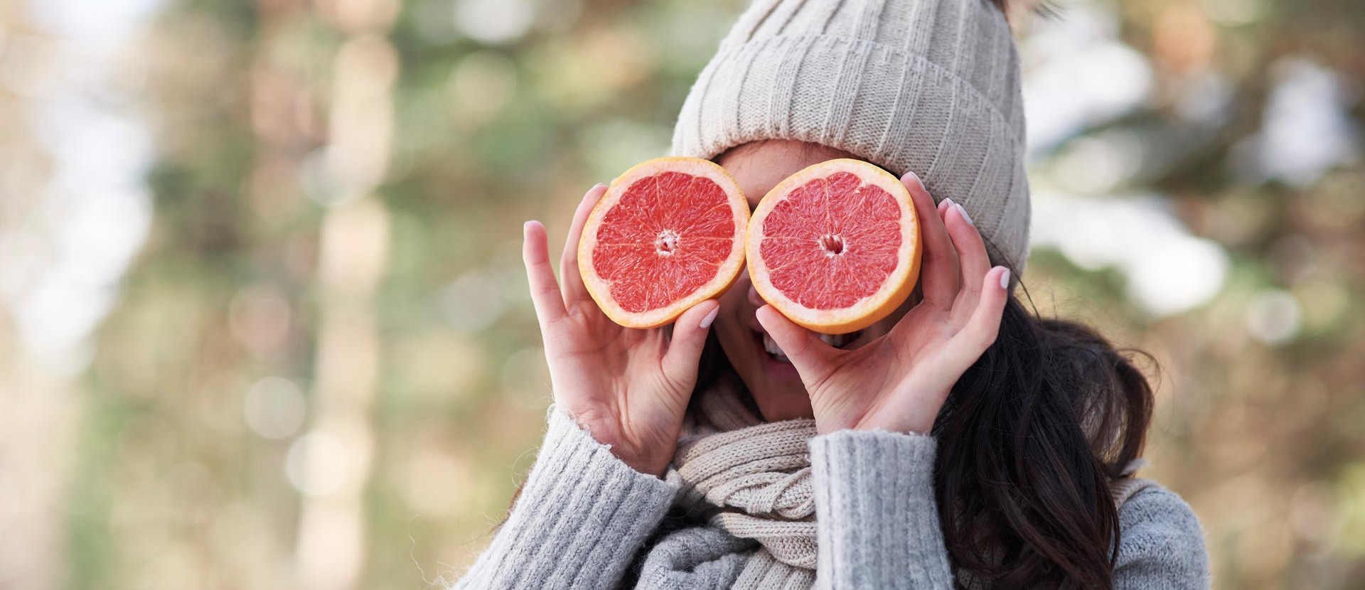 Frau hält sich Grapefruit-Hälften vor die Augen