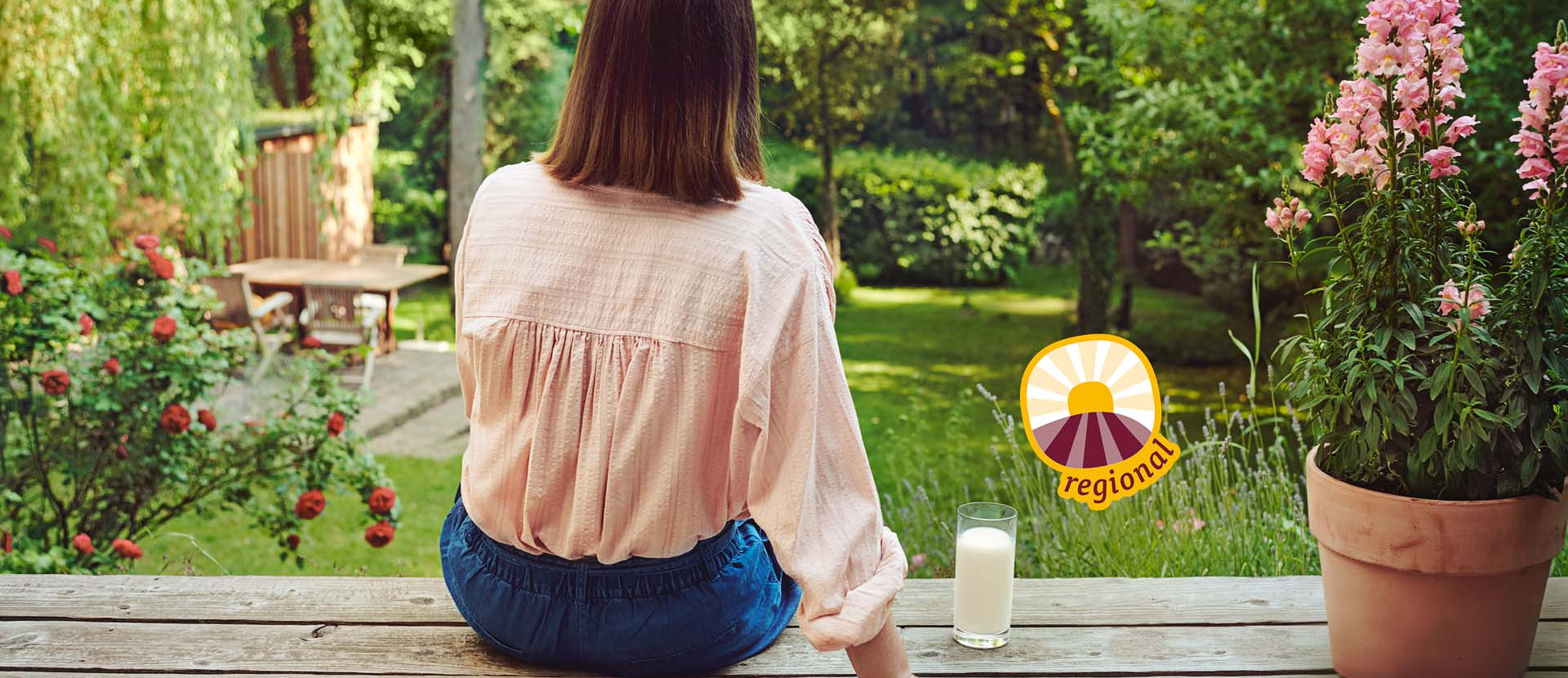 Regionale Produkte Frau sitzt auf Holzterrasse mit Glas Milch