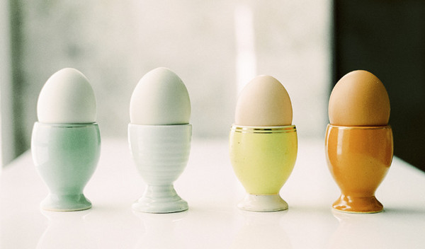 Vier Eierbecher mit Eiern stehen nebeneinander.