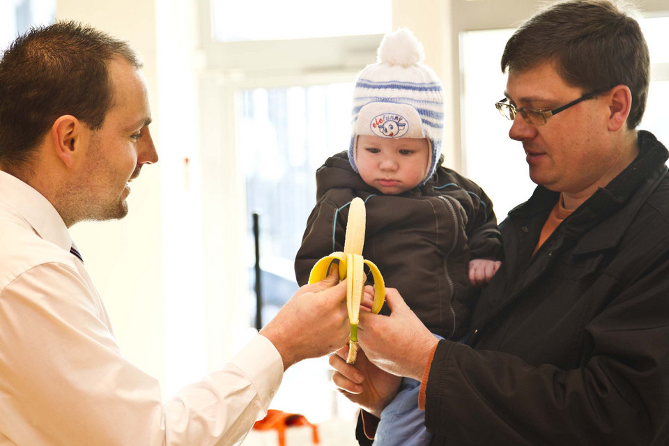 Mitarbeiter gibt einem Kind eine Banane