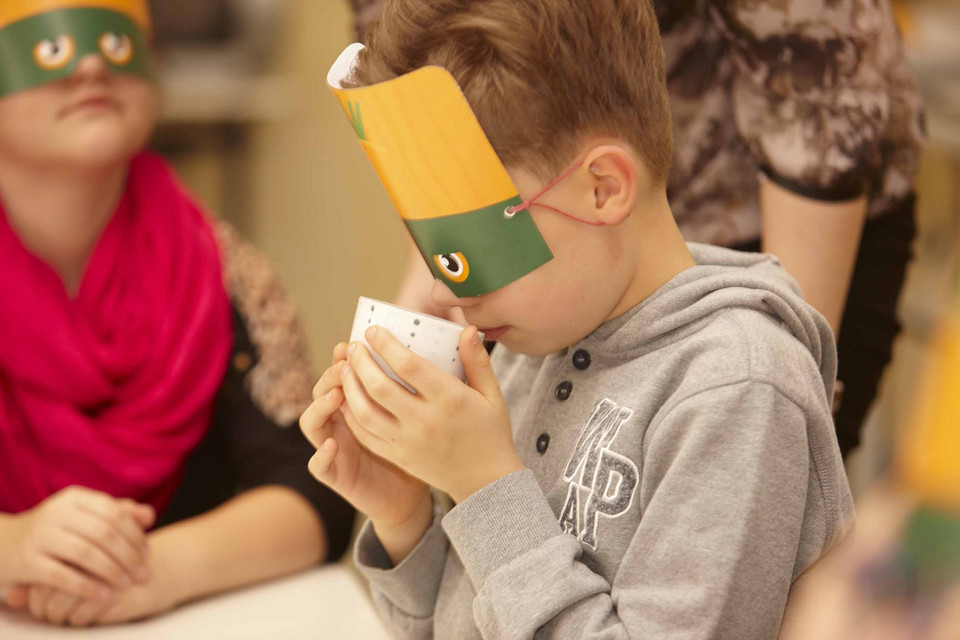 Junge mit Maske riecht an Lebensmitteln in einer Tasse