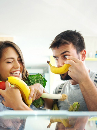 Mann und Frau stehen vor Kühlschrank mit Obst und Gemüse