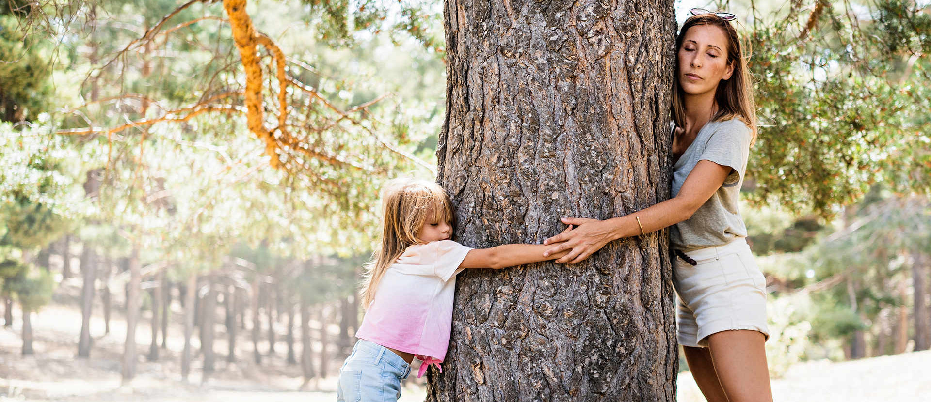 Eine Frau und ein Kind umarmen einen Baum