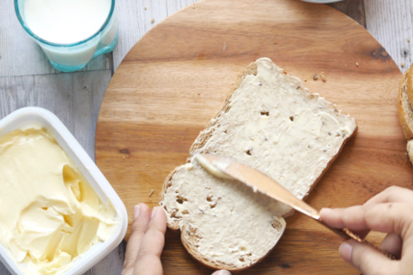 Brot mit Margarine Aufstrich auf einem Tisch mit Holzbrettchen und weiteren Brotscheiben