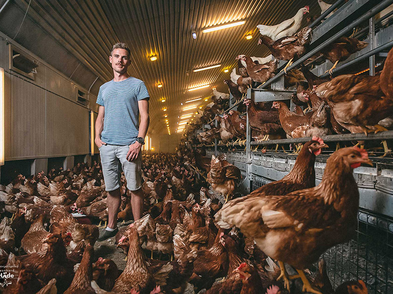 Der Betriebsleiter mit Hühnern im Stall