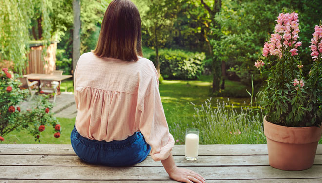 Regionale Produkte Frau sitzt auf Holzterrasse mit Glas Milch