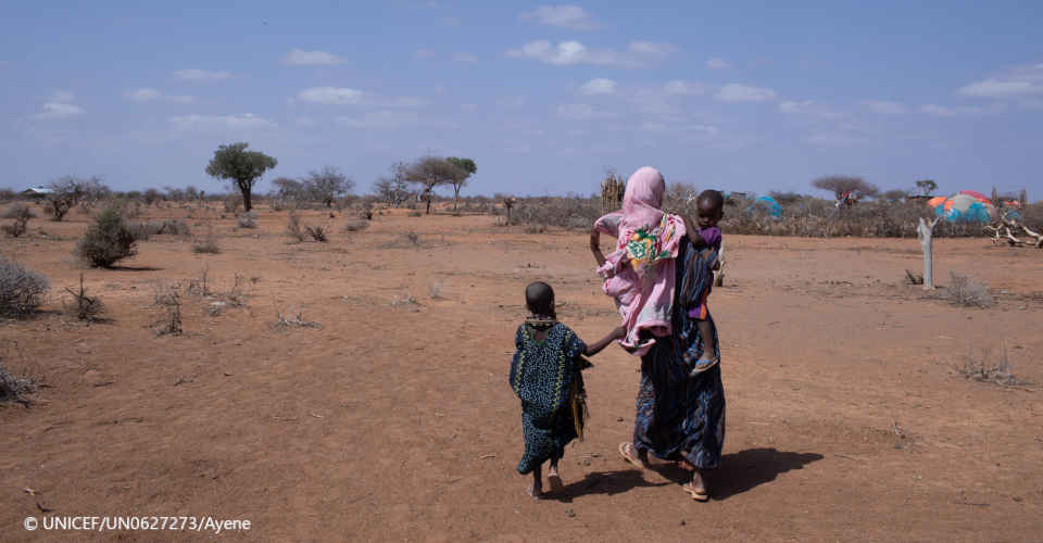 Mutter mit Kindern laufen durch karge Landschaft