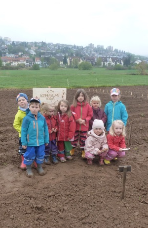 Eine Kindergartengruppe steht auf einem Acker