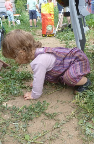 Ein Kind stützt sich mit den Armen auf dem Boden ab, während sie im tegut Saisongraten ist.