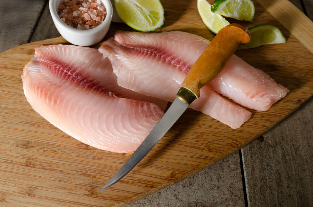 Messer auf zwei Scheiben rohem Fisch