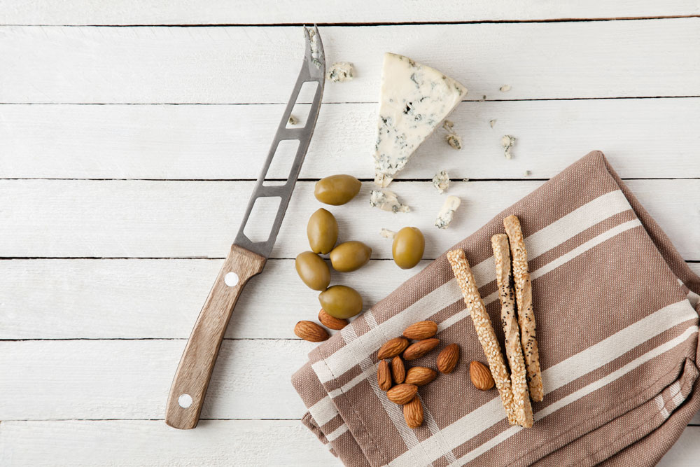Messer mit Oliven, Käse und Geschirrtuch