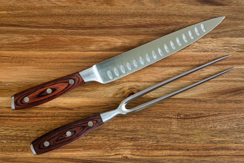 Messer und Tranchiergabel auf Holzbrett 