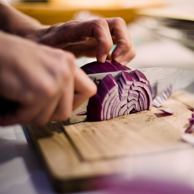 Küchen Hacks: Eine Zwiebel wird in Stücke auf dem Holzbrettchen geschnitten
