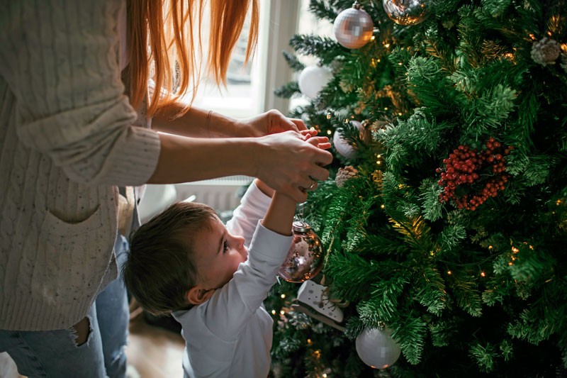 Kind schmückt einen Weihnachtsbaum