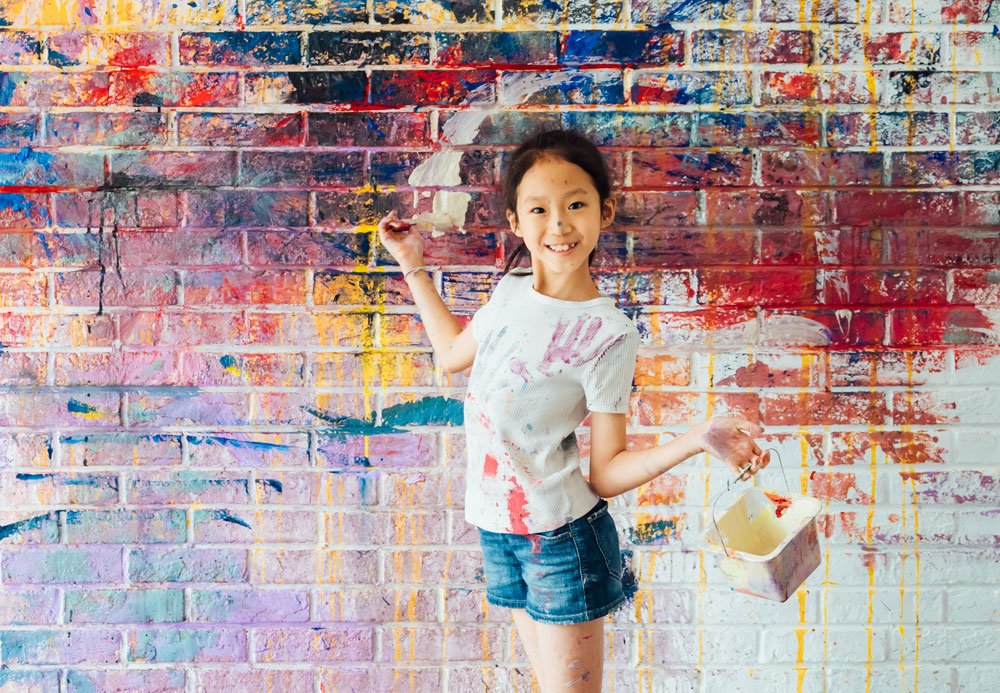 Mädchen vor bunter Wand mit Farben