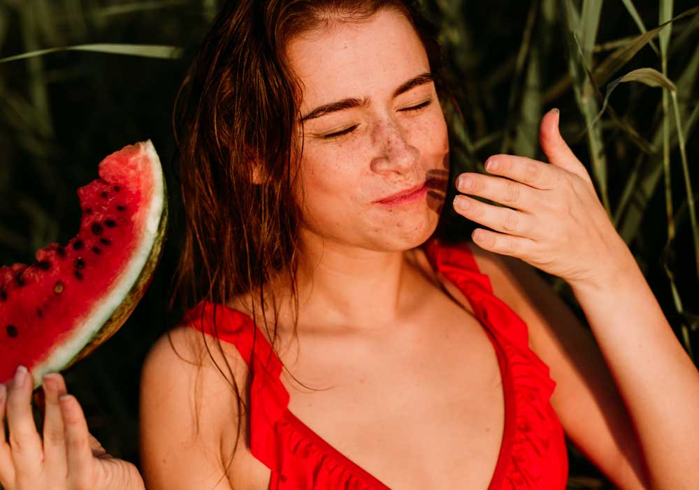 Frau im roten Bikini isst Melone