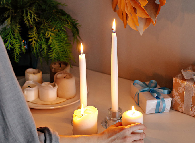 Eine Frau dekoriert eine Kommode mit Kerzen.