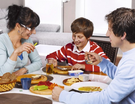 Familie sitzt am Tisch mit gesunden Lebensmitteln