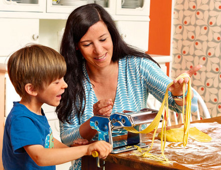 Mutter und Kind machen Nudeln mit Nudelmaschine