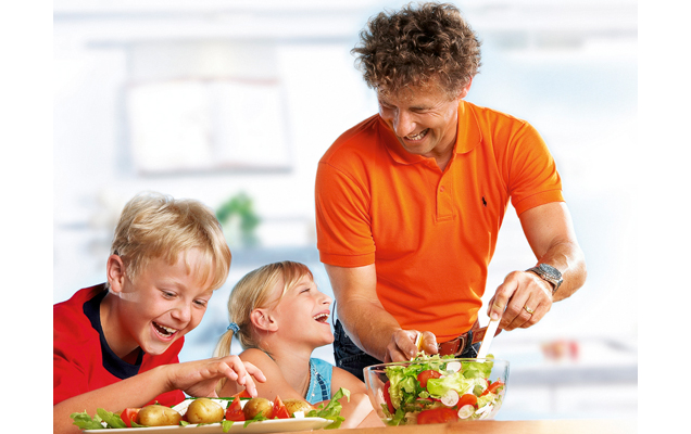 Kinder mit Vater beim Salat zurbereiten